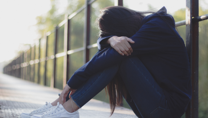 Teen with forehead on knees