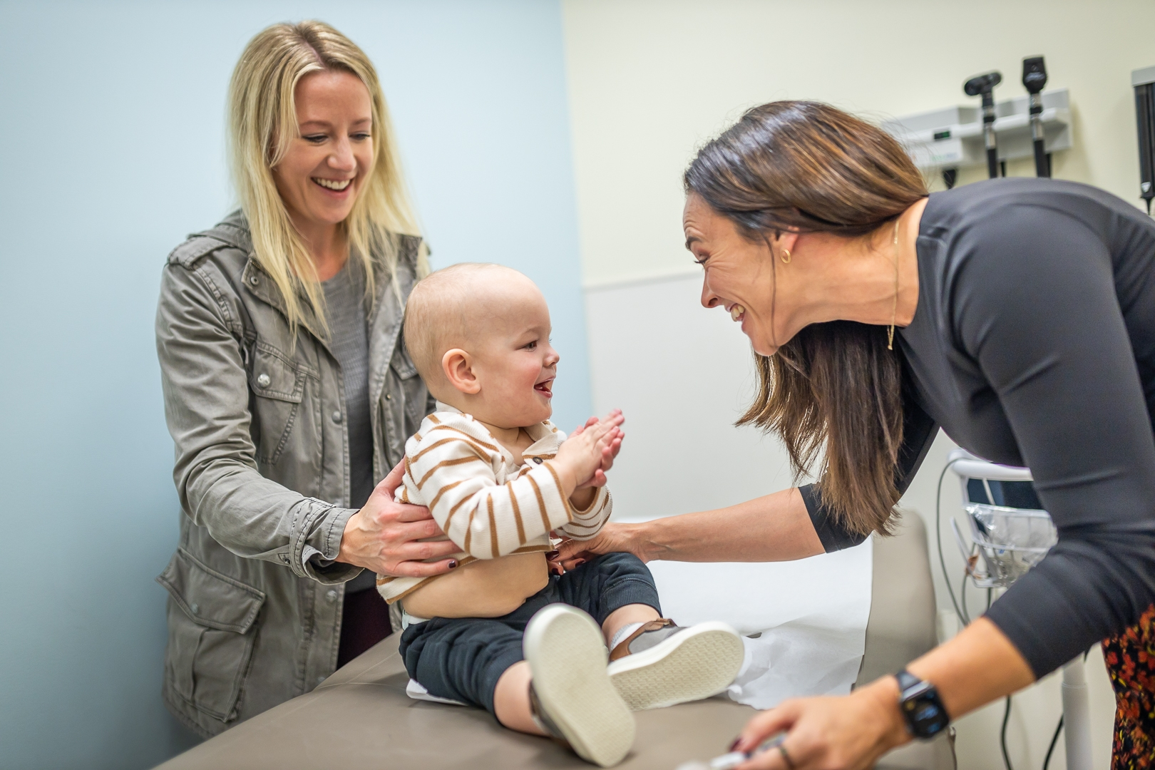 Mother and baby smiling with a nurse.